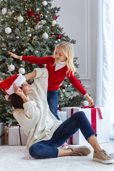 Lady i en tomte hatt ler mot sitt barn — Stockfoto