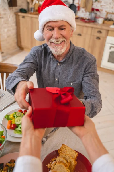 Tipo hombre de pelo gris mirando a la caja roja — Foto de Stock