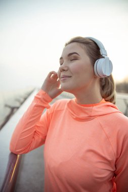 Kulaklıklı hoş bayan dışarıda müzik dinliyor.