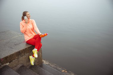 Dışarıda cep telefonuyla konuşan güzel genç bir kadın.