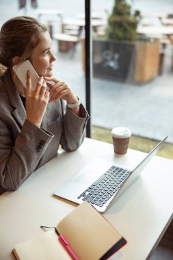 Cafe 'de cep telefonuyla konuşan hoş bir genç kadın.