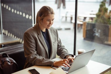 Kafede dizüstü bilgisayarda çalışan çekici genç kadın