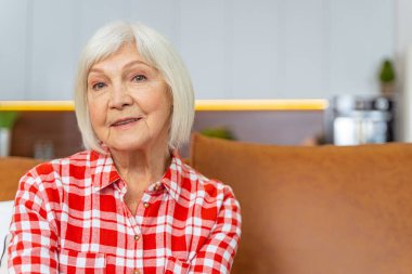 Kanepede oturan gülümseyen yaşlı bayan.