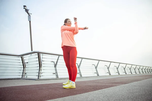 Charmante sportieve dame die zich uitstrekt over de brug — Stockfoto