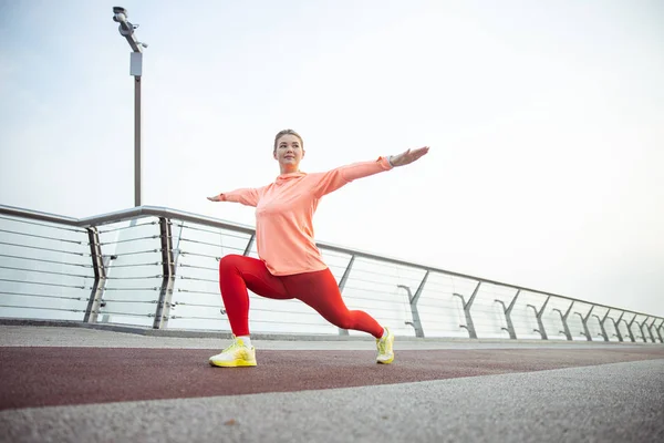 Aantrekkelijke jonge vrouw die zich uitstrekt over de brug — Stockfoto