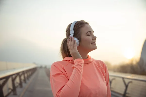 Linda dama escuchando música a través de auriculares inalámbricos — Foto de Stock