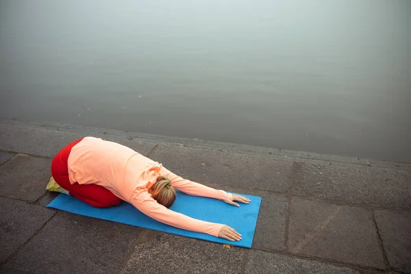 Mujer joven practicando yoga junto al río —  Fotos de Stock