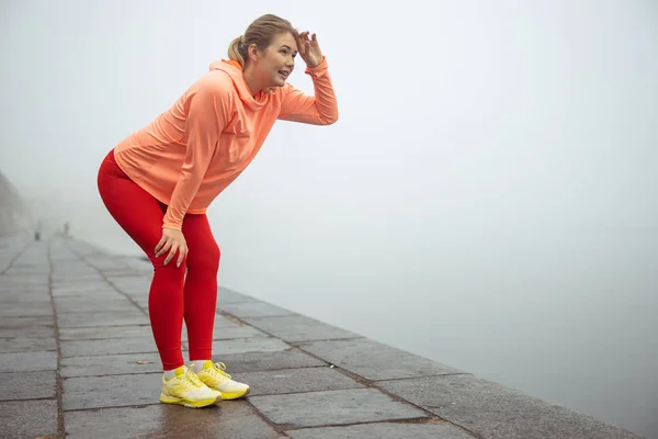 Sportliche Dame steht gebückt auf der Straße — Stockfoto