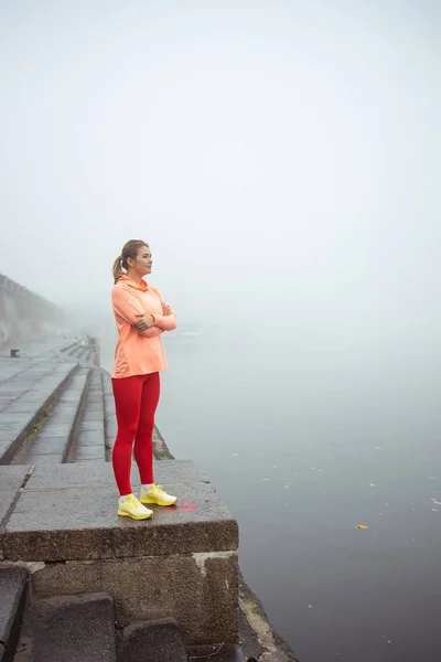 Mujer joven deportiva de pie junto al río — Foto de Stock