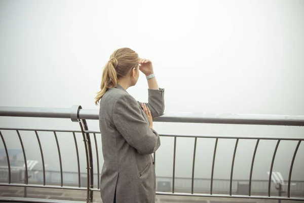 Junge Frau in Jacke steht auf dem Balkon — Stockfoto
