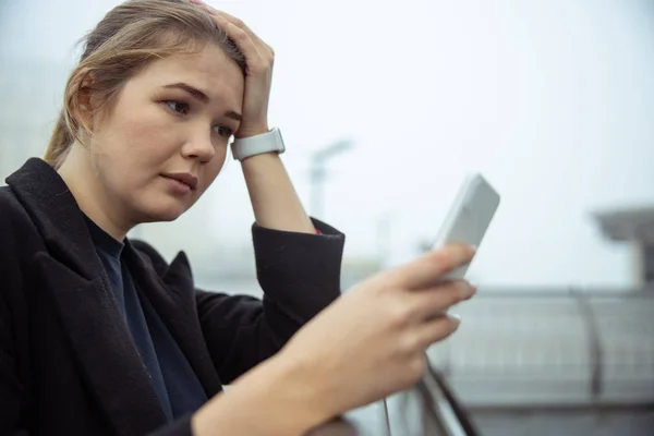 Расстроенная молодая женщина, использующая мобильный телефон на улице — стоковое фото