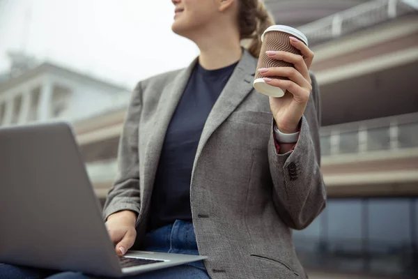 Stylowa pani z laptopem na kolanach trzyma filiżankę kawy — Zdjęcie stockowe