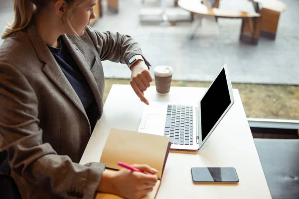 Pretty lady looking at watch while working in cafe — Stock Photo, Image