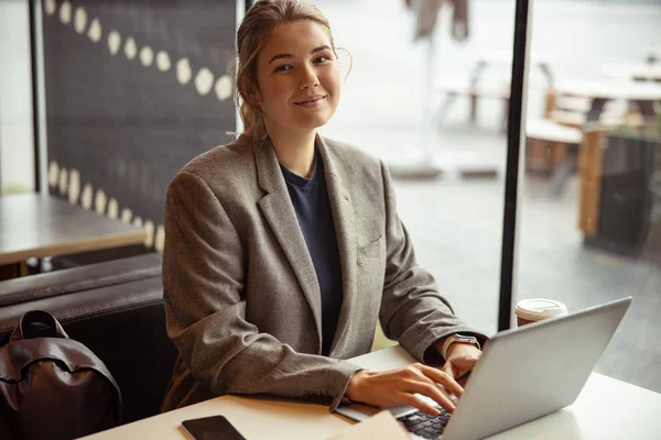 Mooie jonge vrouw die op laptop in café werkt — Stockfoto