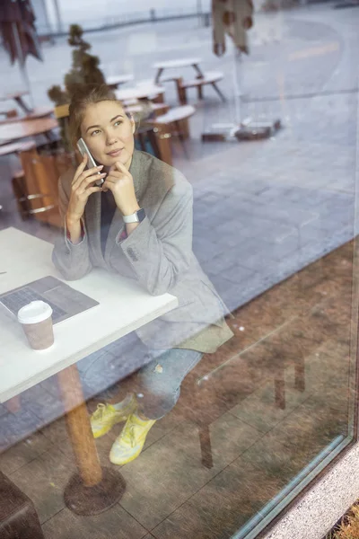 Atraktivní mladá žena mluví na mobilu v kavárně — Stock fotografie