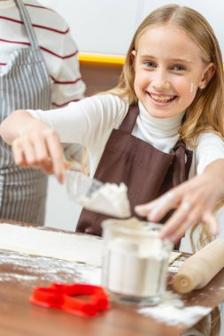 Önlüklü neşeli kız kameraya poz veriyor.