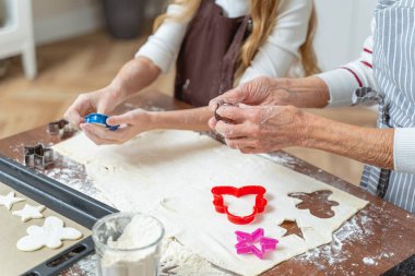 Dişiler yuvarlanmış hamur üzerinde bisküvi kesiyor.