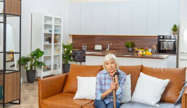 Elinde baston olan yalnız, yaşlı bir kadın.