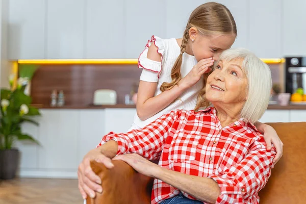 Kleindochter vertelt een geheim aan een oudere vrouw — Stockfoto