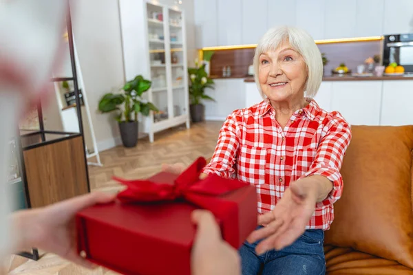 Överraskad äldre kaukasiska kvinna som får en gåva — Stockfoto