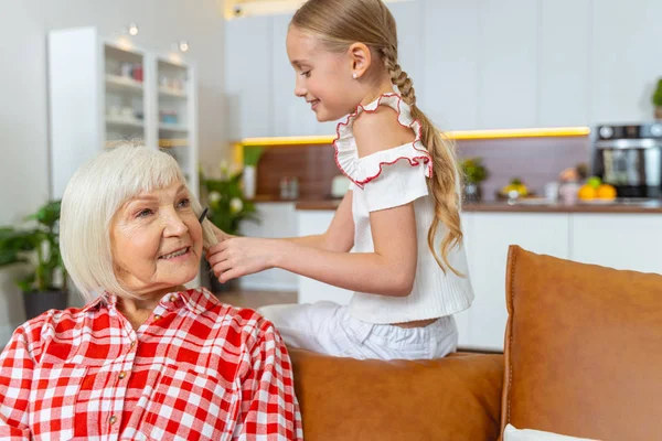 Usmívající se dívka kartáčování starší ženy vlasy — Stock fotografie