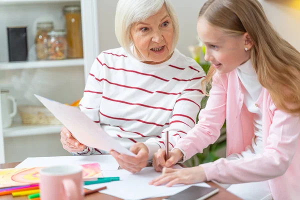 Mujer mayor enseñando dibujo a su nieta bonita — Foto de Stock