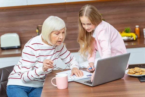 Serious female and her granddaughter looking at the calendar — Stock Photo, Image