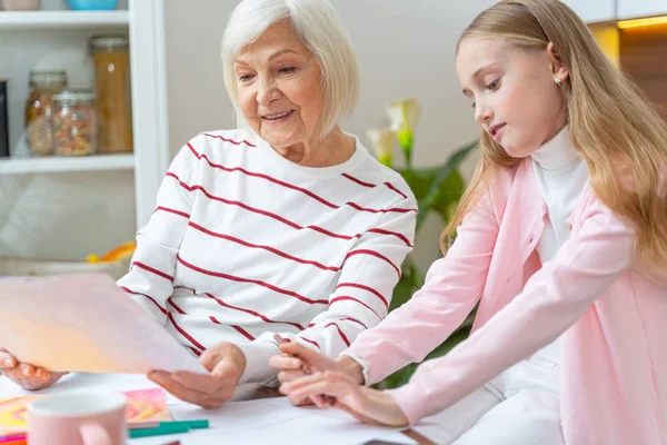 Nöjd äldre dam tittar på hennes barnbarn ritning — Stockfoto