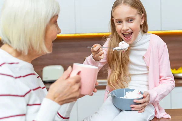 Abuela con una taza mirando a su nieta —  Fotos de Stock