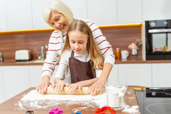 Mormor och hennes barnbarn rullar ut degen — Stockfoto