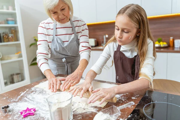 Chica trabajando con su abuela en la cocina —  Fotos de Stock