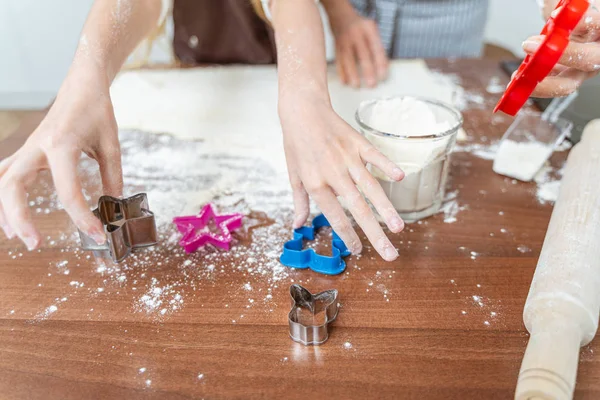 Ragazza che prende stampi per biscotti dal tavolo — Foto Stock