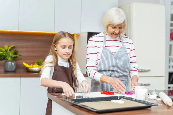 Mulher idosa alegre colocando cortadores de biscoitos na pastelaria — Fotografia de Stock