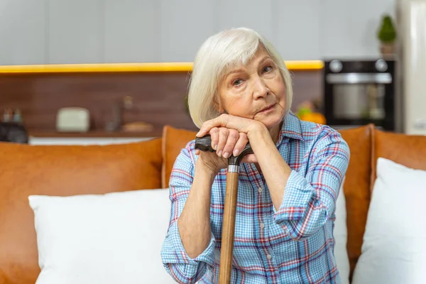 Frau mit Stock sitzt im Zimmer — Stockfoto