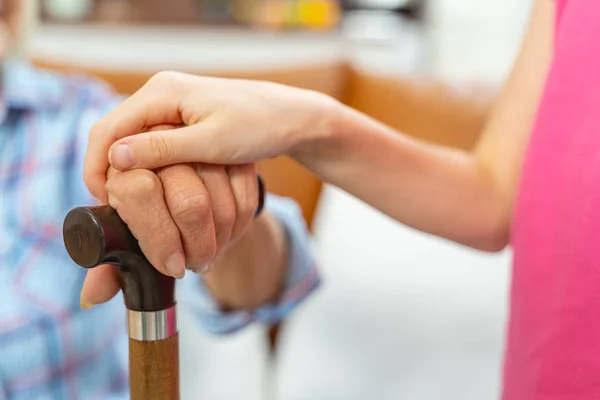 Jeune main féminine touchant une main de pensionné — Photo