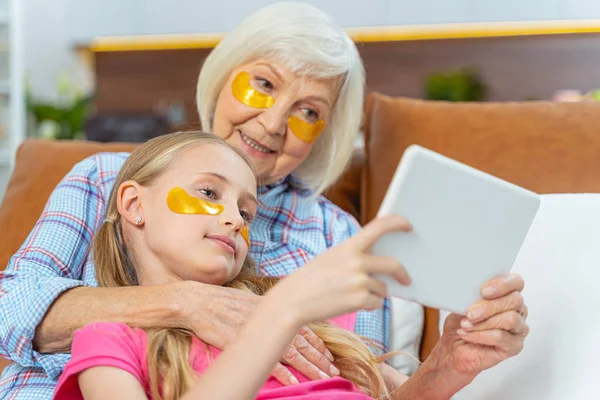 Mujer sonriente y su nieta usando una tableta —  Fotos de Stock