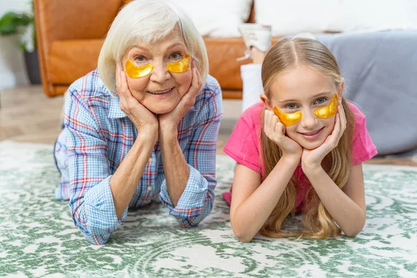 Meisje en haar oma dragen collageen oogkussens — Stockfoto