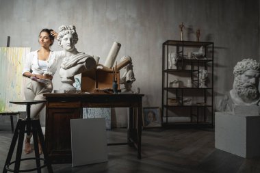 Heykelin yanında poz veren alımlı genç kadın sanatçı.