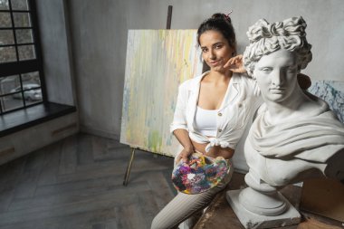 Heykelin yanında poz veren güzel genç kadın sanatçı.