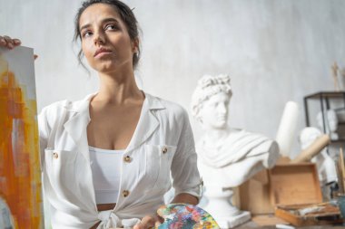 Sakin bir sanatçı sehpanın yanında poz veriyor.