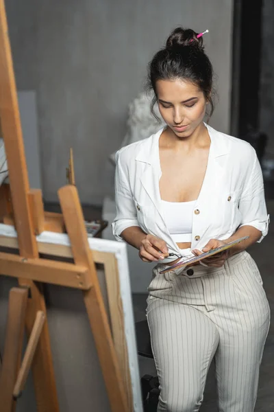 Encantadora joven artista mirando sus brazos — Foto de Stock