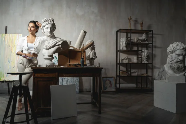 Heykelin yanında poz veren alımlı genç kadın sanatçı.