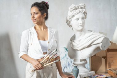 Beyaz kadın sanat odasında yeni bir tablo çizmek için toplanıyor.