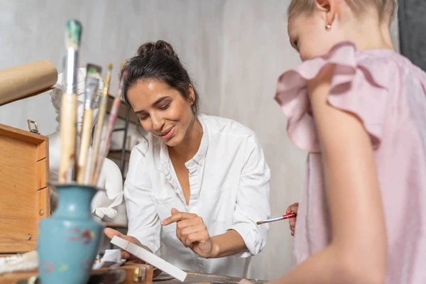 Branco feminino artista ensinando bonito menina para pintar no arte lição — Fotografia de Stock