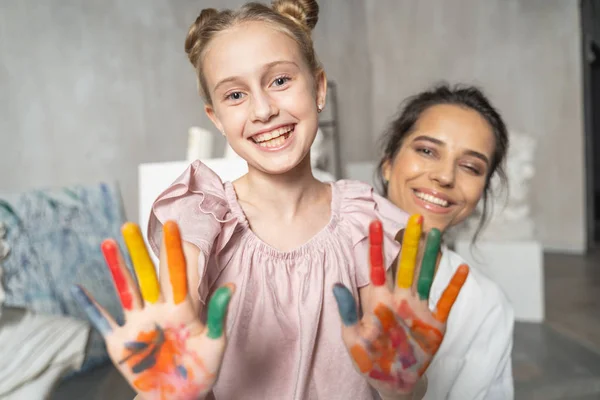 Cheerful daughter with painted palms having fun with her beautiful mother — Stock Photo, Image