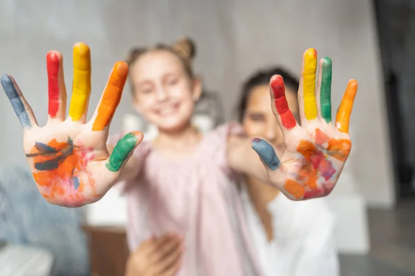 Liten rolig flicka som visar målade färgade handflator till kameran — Stockfoto