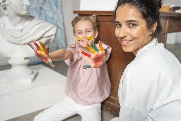 Mała ładna dziewczyna pokazując kolorowe dłonie do kamery — Zdjęcie stockowe