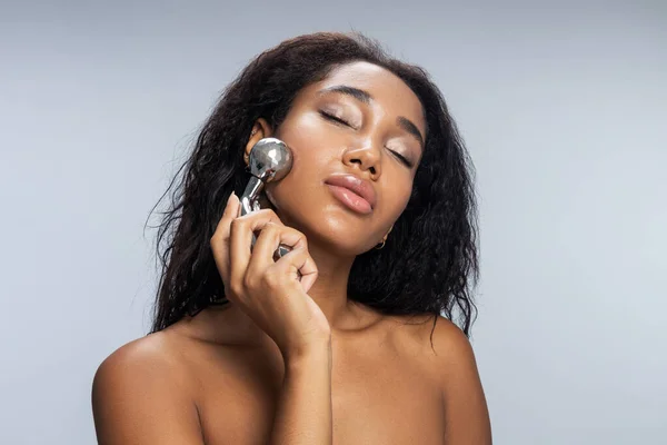 Pretty young lady with closed eyes making facial massage — Stock Photo, Image