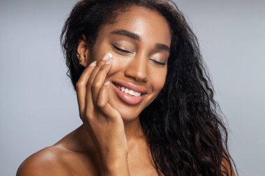 Güzel Afro kadın yüz kremi sürüyor.