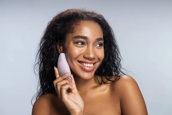 Lächelnde Afroamerikanerin hält Silikonbürste für Gesicht in der Hand — Stockfoto